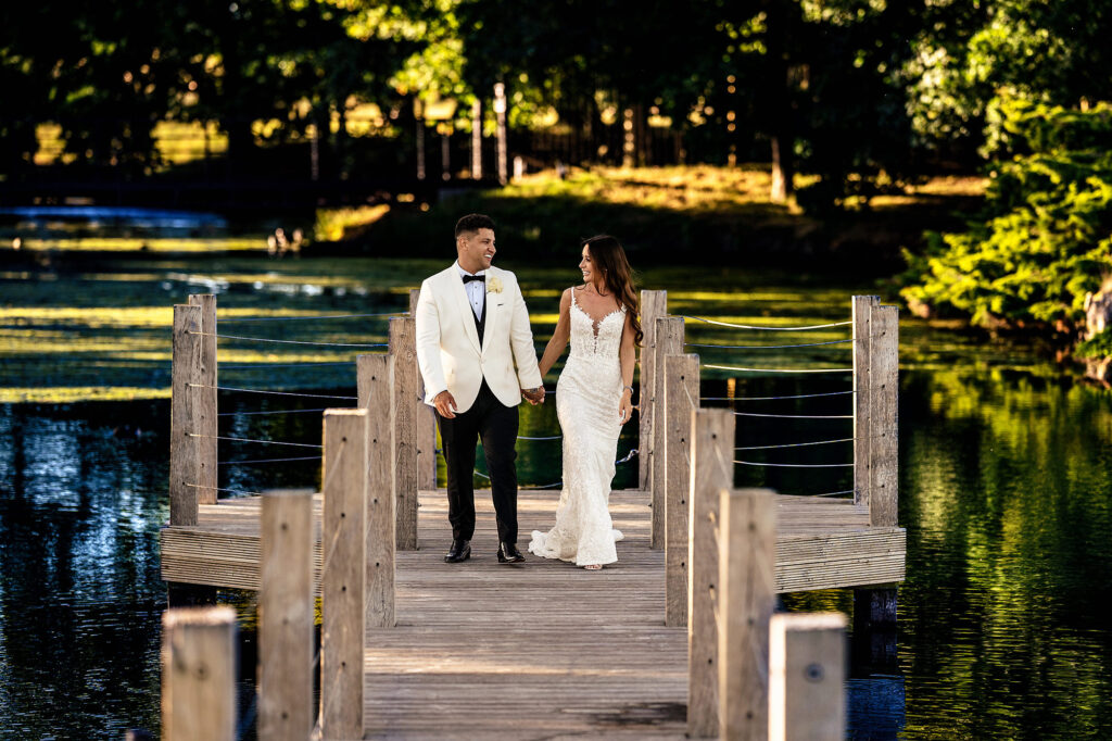 Gemma and Tyrone walking hand in hand along the jetty over the lake at Merrydale Manor in evening light