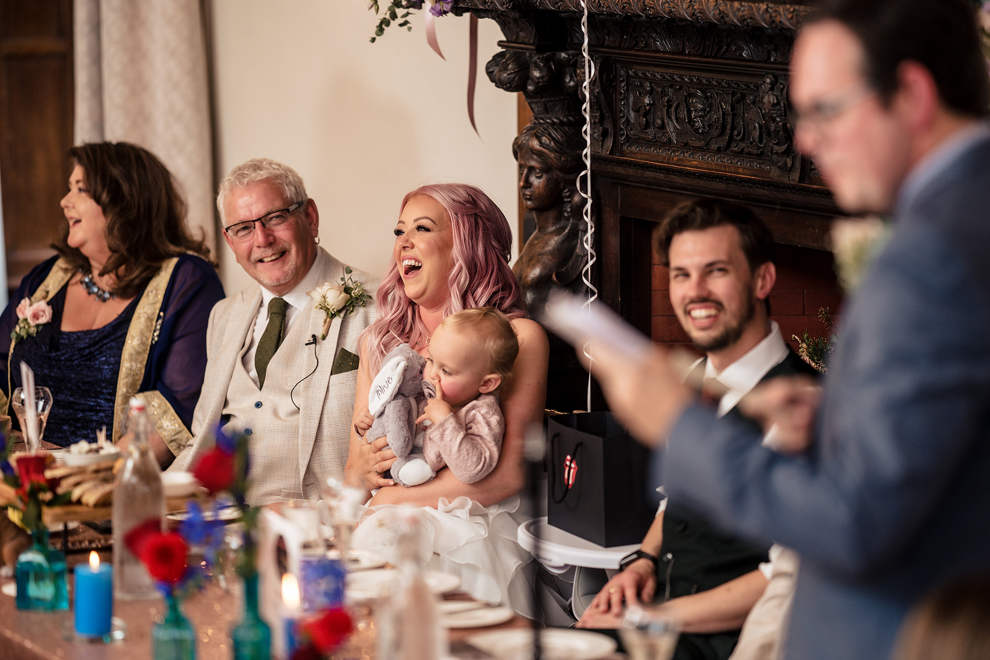 Bride, groom and their families laughing together at the top table during the speeches at Standon Hall
