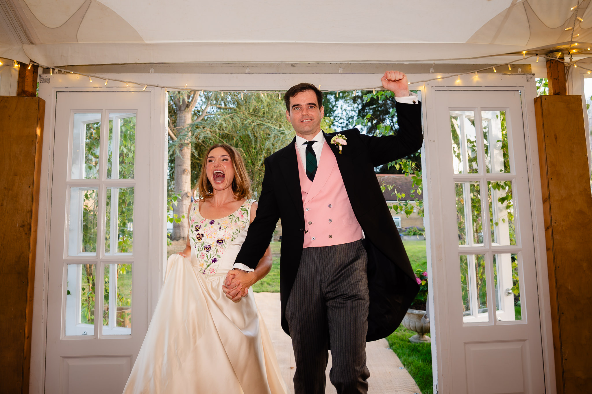 Bride and groom bursting through the doors into the marquee to cheers from their guests