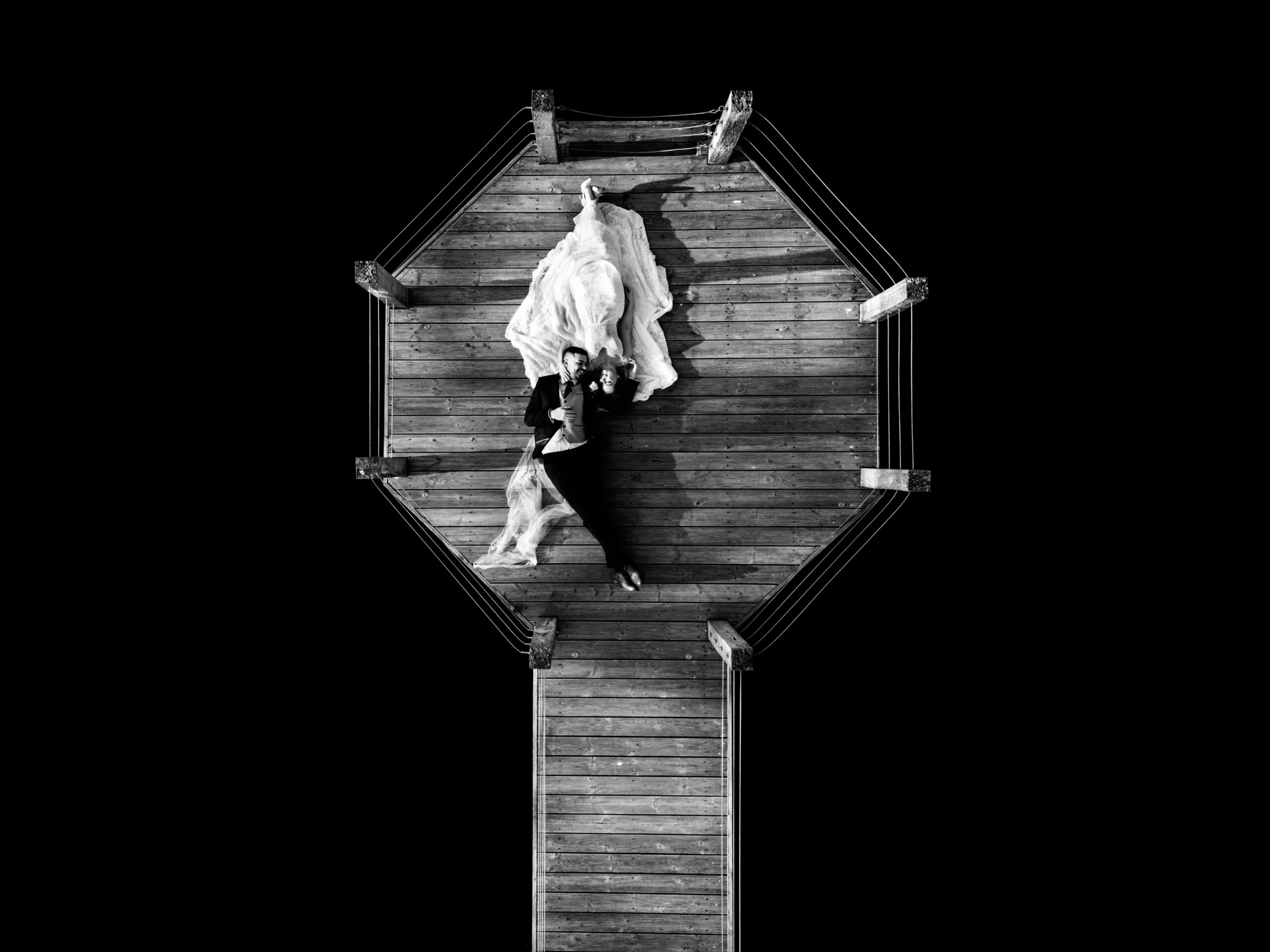 Black and white drone photo looking straight down on Dean and Bethany on the octagonal platform at the end of the jetty