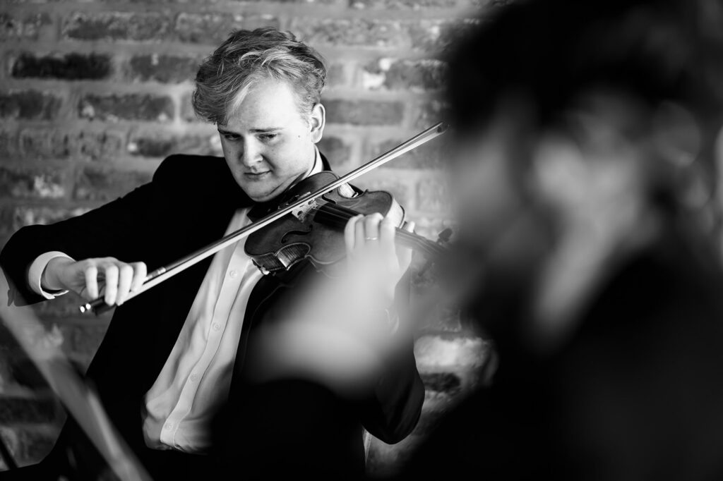 Black and white of a violinist playing during the wedding breakfast entrance, Nottingham wedding photographer