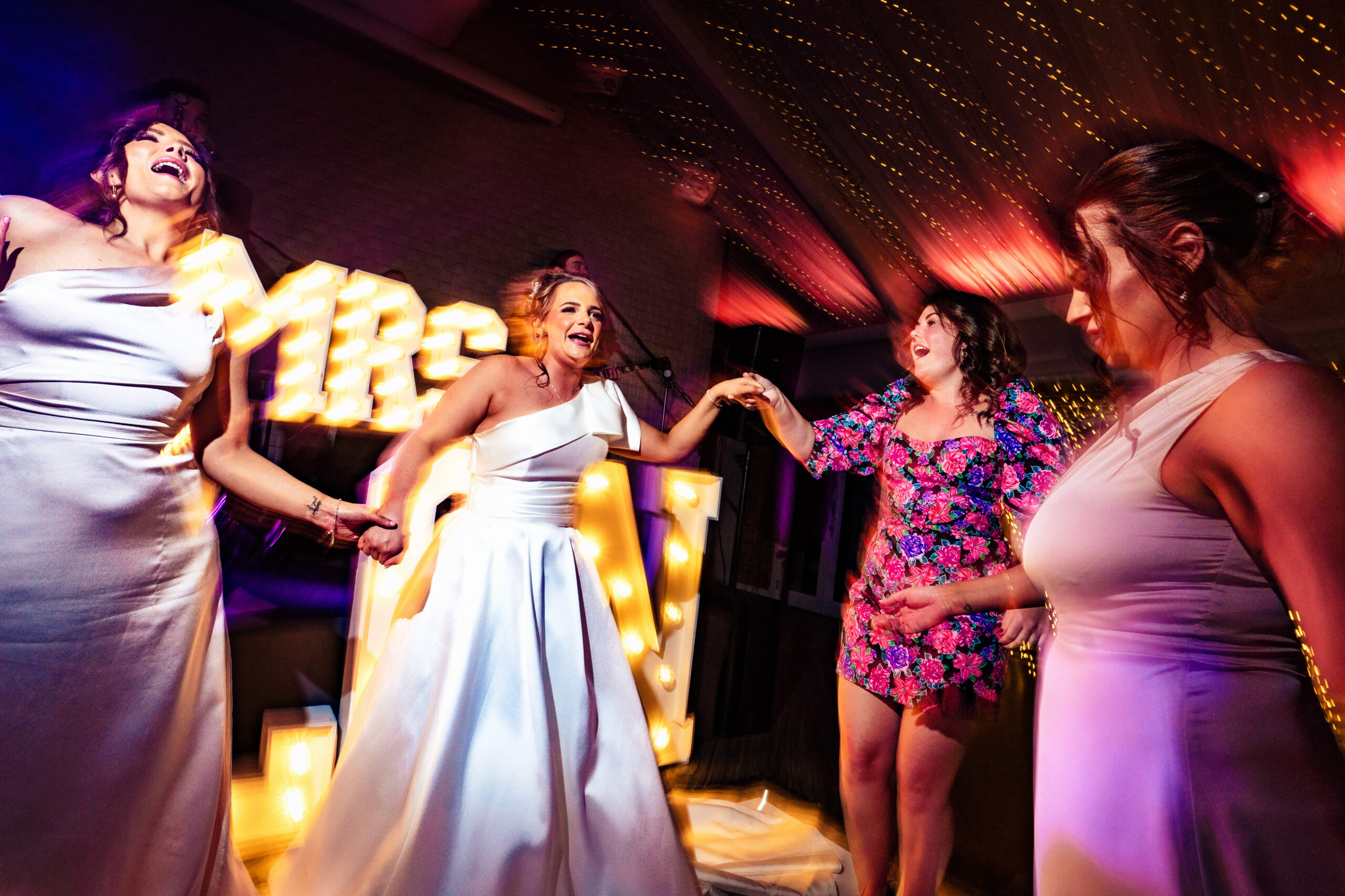 Georgia singing along with her bridesmaids under the light up letters