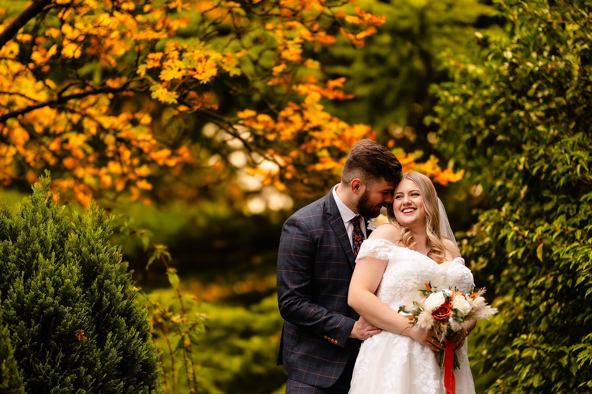 Annie and Tom sharing an embrace among Crewe Hall’s autumn trees, Cheshire wedding photographer