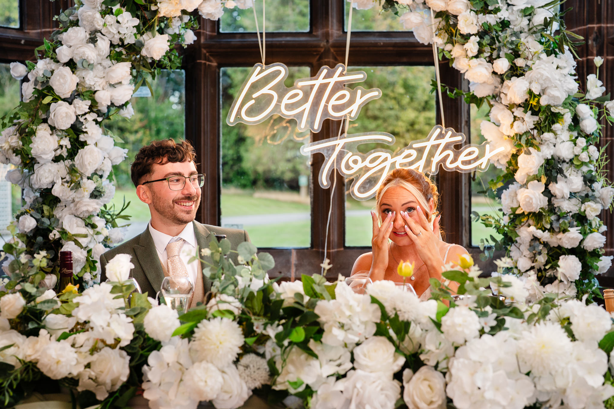 Bride wiping away tears beneath a neon Better Together sign during speeches at Salt House