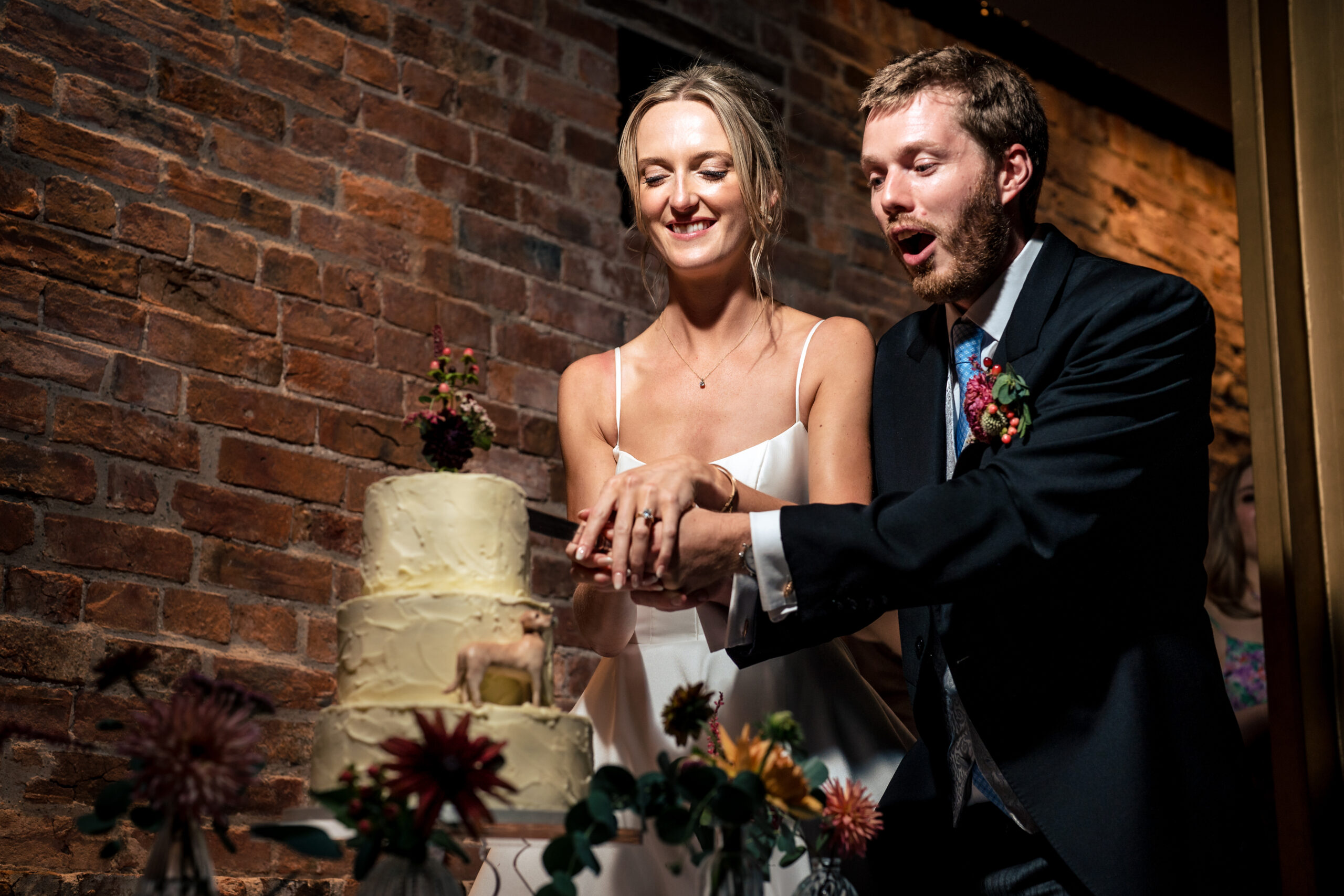 Bride and groom pulling faces as they cut their wedding cake at Dorfold Hall