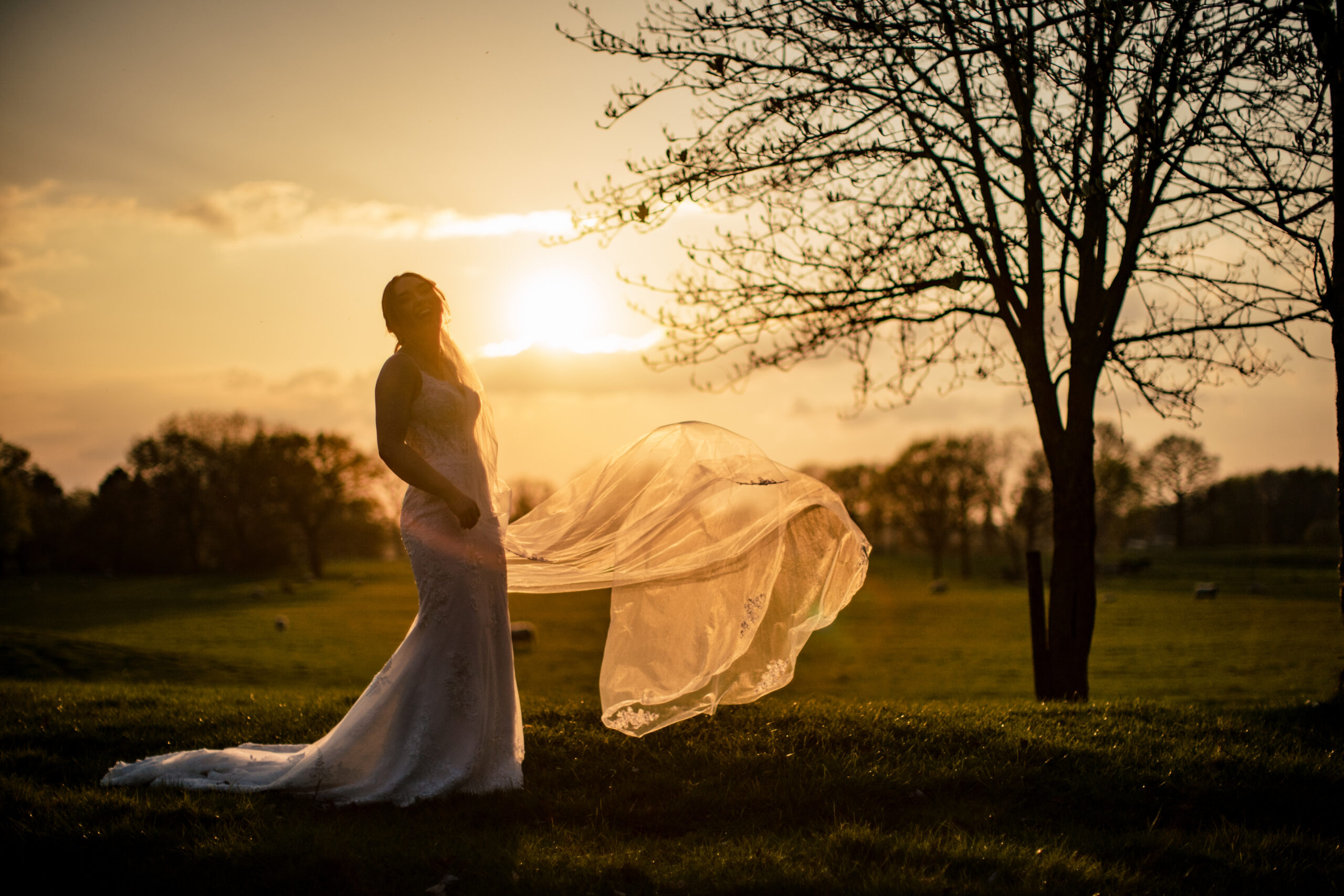 Bethany silhouetted against the setting sun with her veil flying out beside her