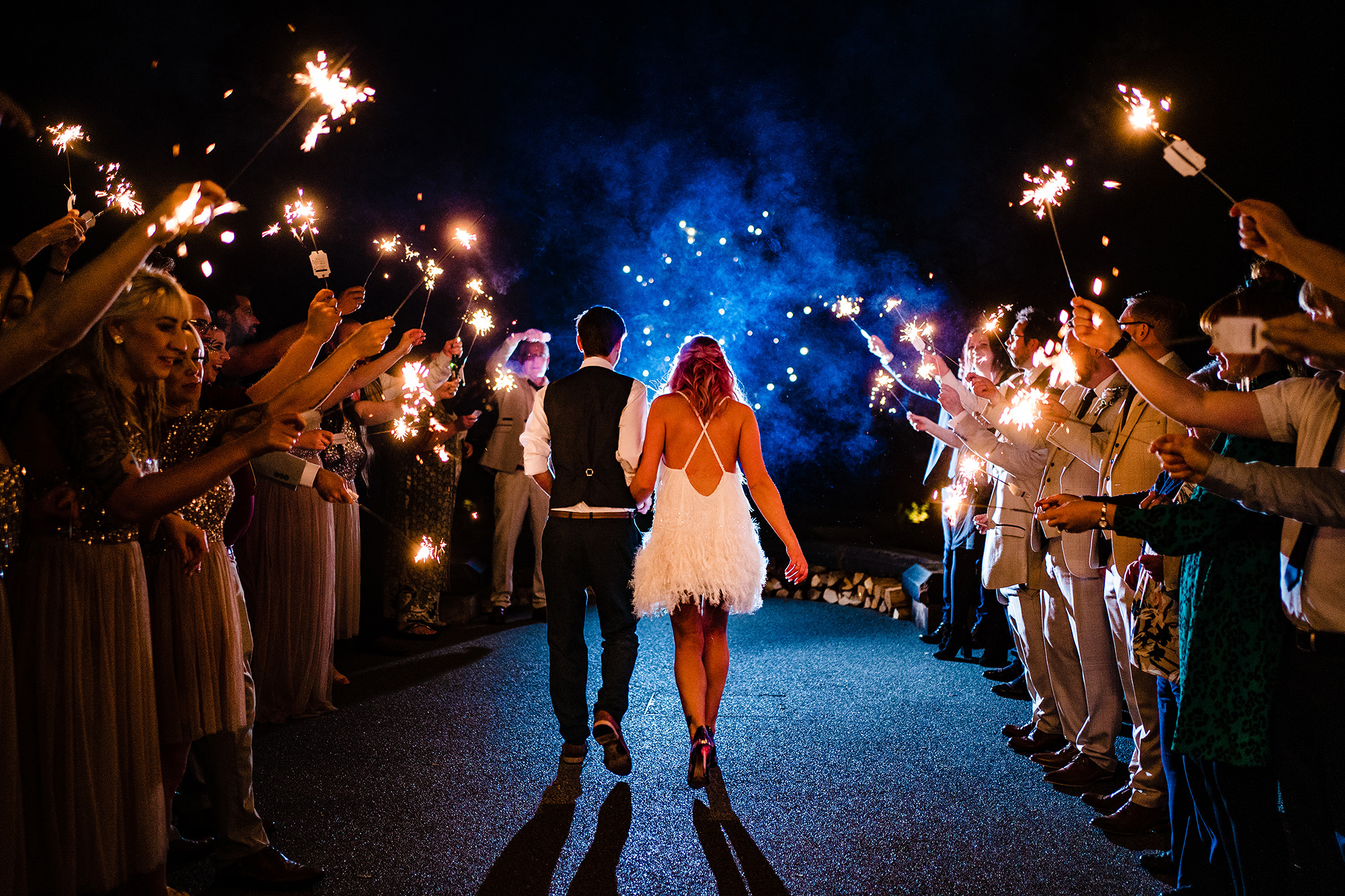 Bride and groom walking away through a sparkler tunnel at the end of their Standon Hall wedding