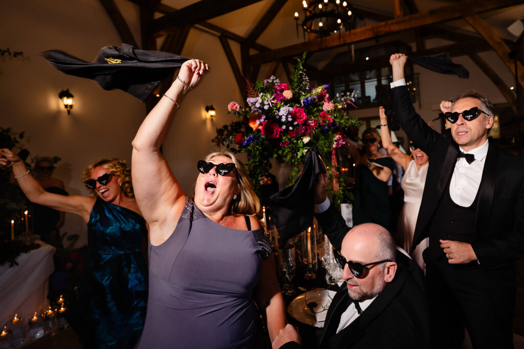 Guests in sunglasses waving napkins over their heads as Kim and Glynn arrive, Nottingham wedding photographer