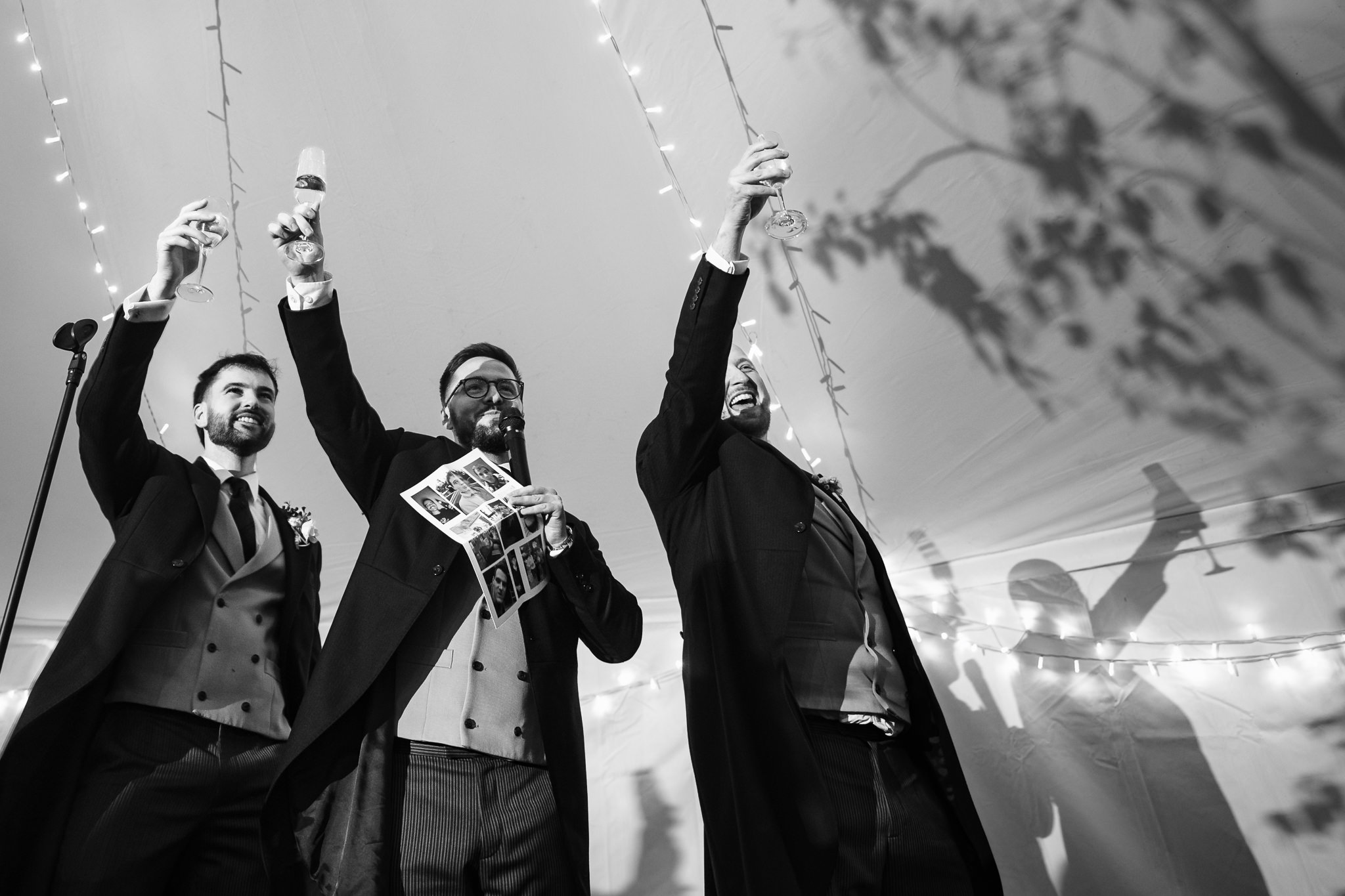 Black and white photograph of the ushers raising a toast to the newlyweds