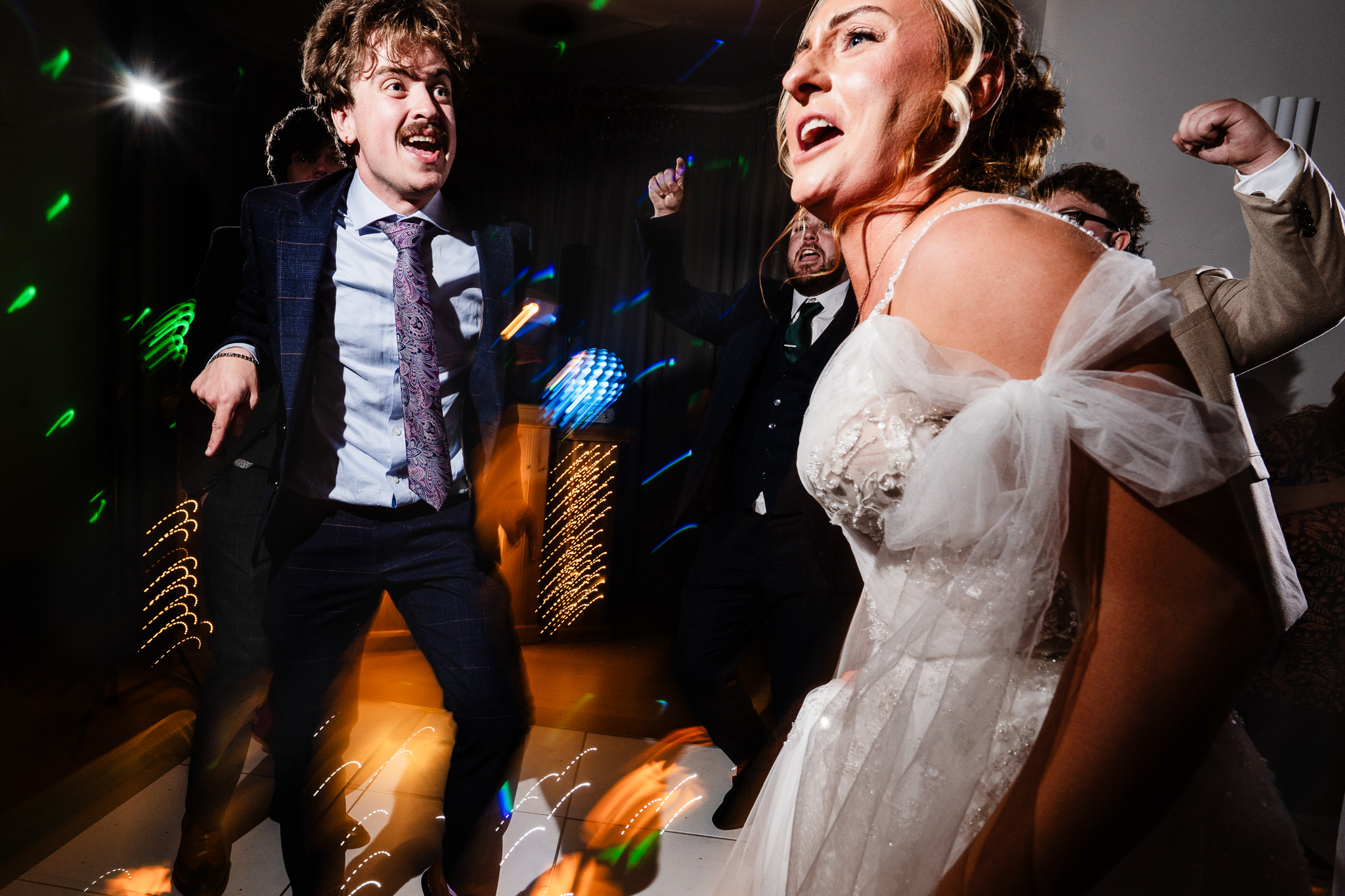 The bride singing along on the dance floor with the groom and friends around her