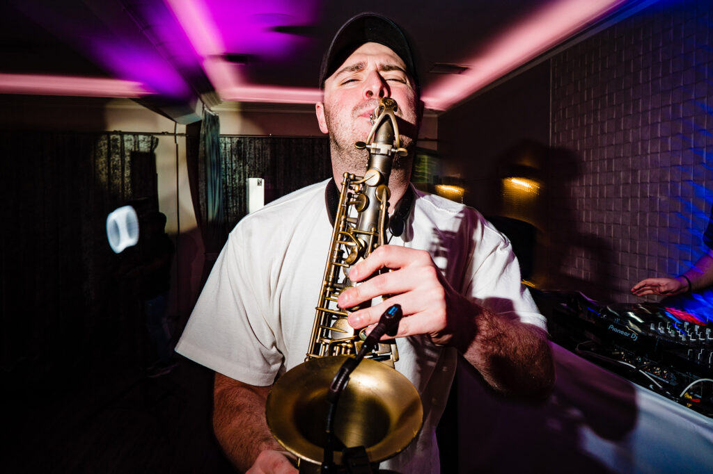 Saxophone player performing next to the DJ decks during the evening party at Merrydale Manor