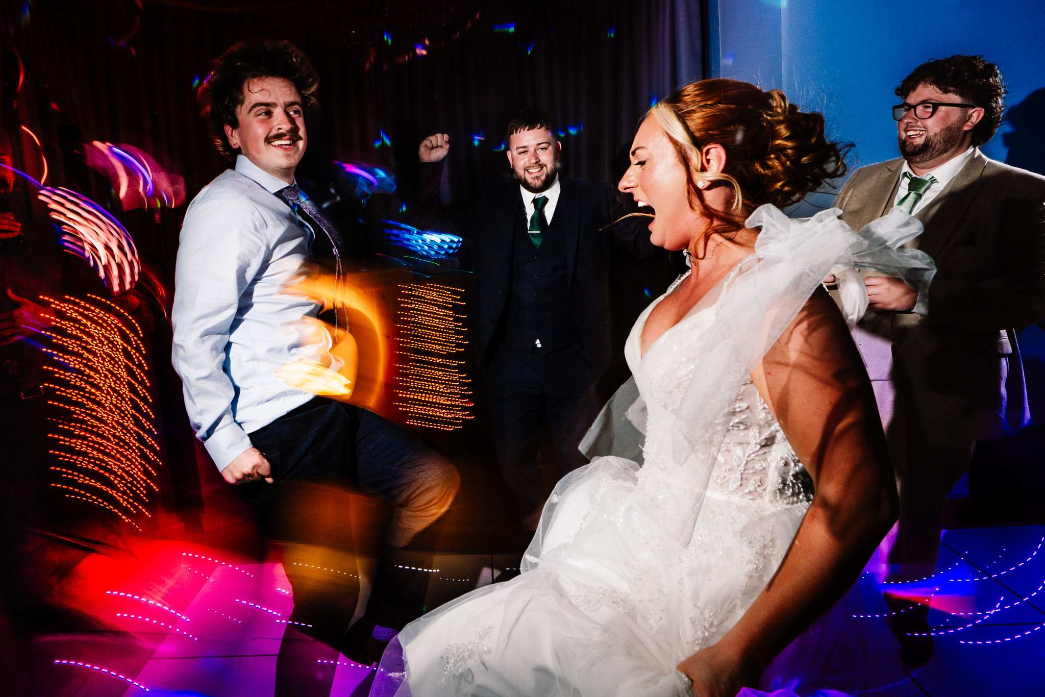 Bride laughing on the dance floor surrounded by guests during the evening party