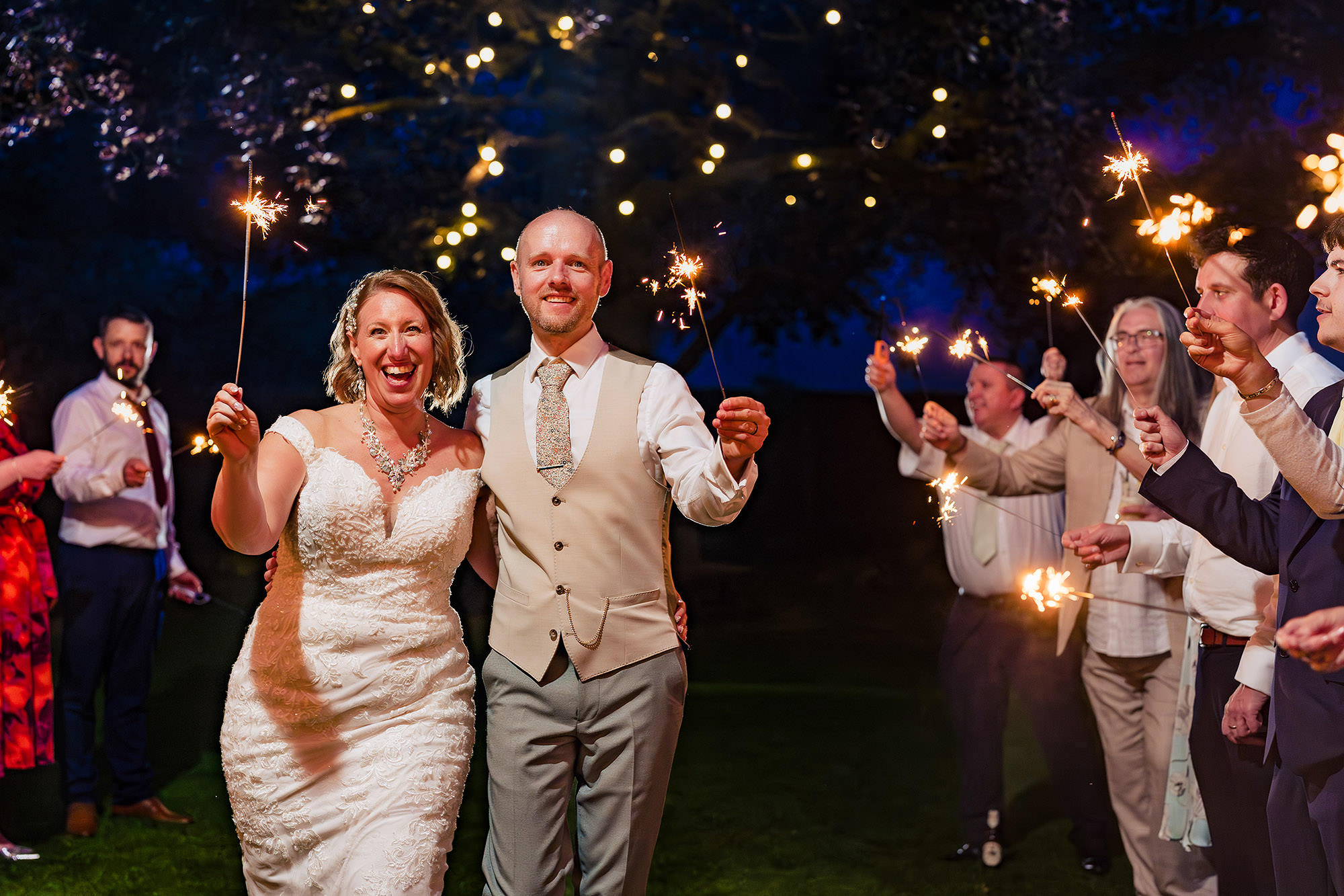 Bride and groom holding sparklers together on the lawn at Salt House as the evening party continued