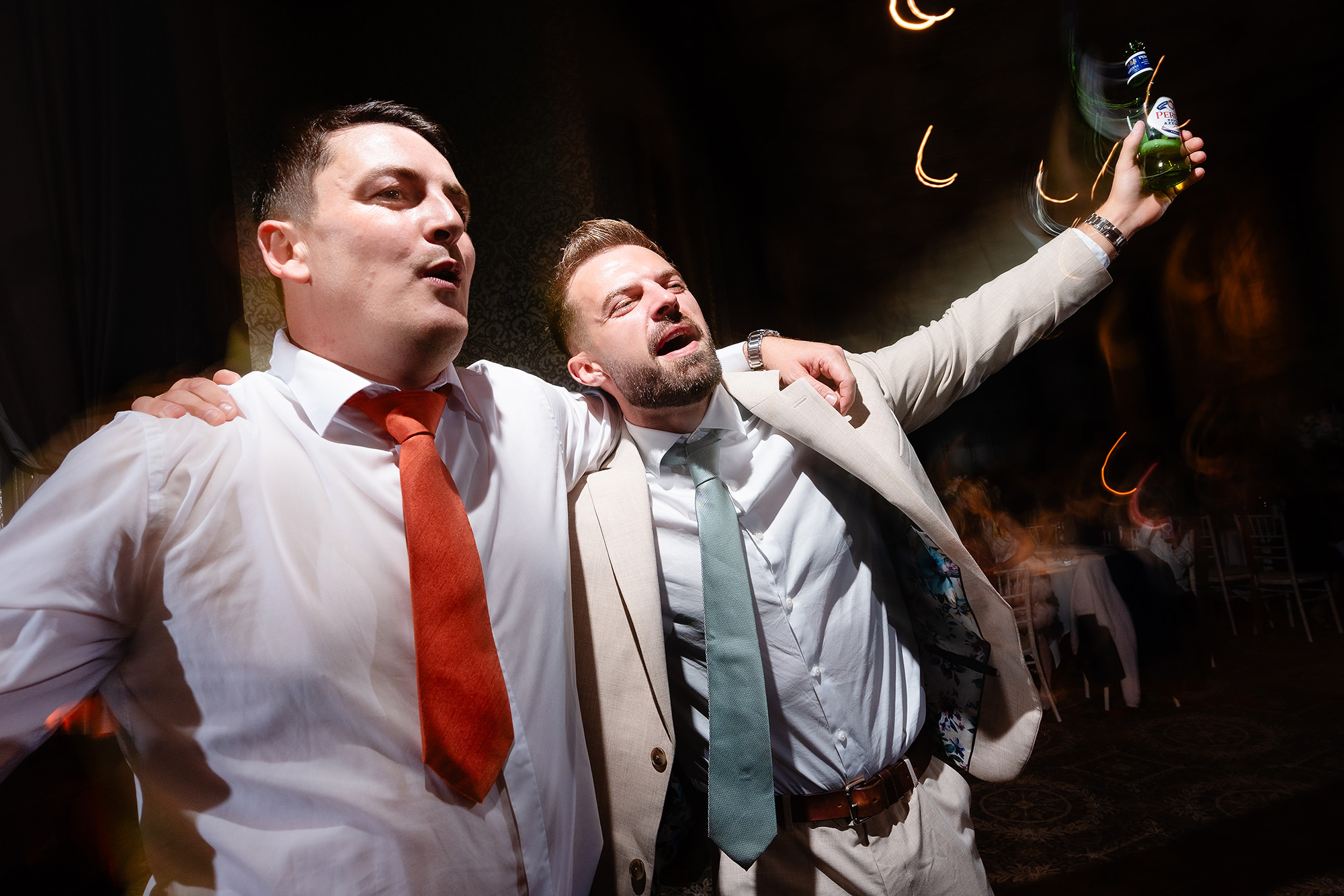 Two guests singing their hearts out arm in arm, trails of coloured light swirling around them