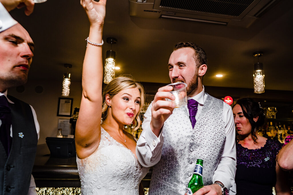 Bride and groom raising their arms and cheering at the bar late in the evening, Merrydale Manor wedding photographer