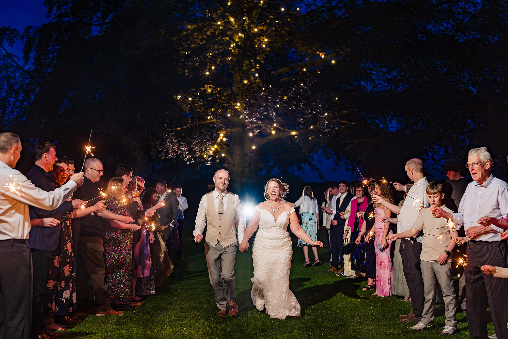 Wedding guests forming a sparkler tunnel for the bride and groom in the grounds at Salt House
