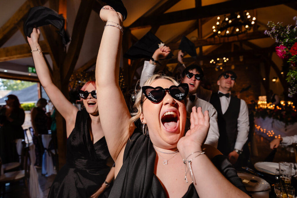 Guests in heart shaped sunglasses screaming and waving napkins, Swancar Farm wedding photographer