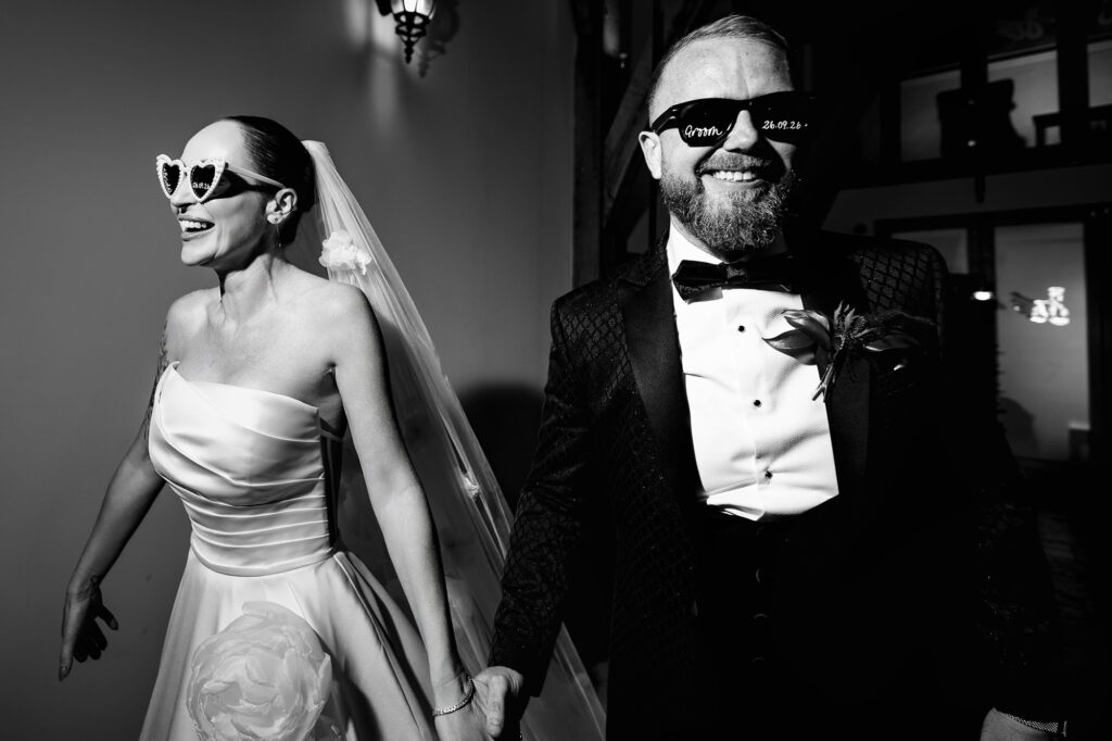 Black and white of Kim and Glynn walking in wearing their personalised sunglasses, Nottingham wedding photographer