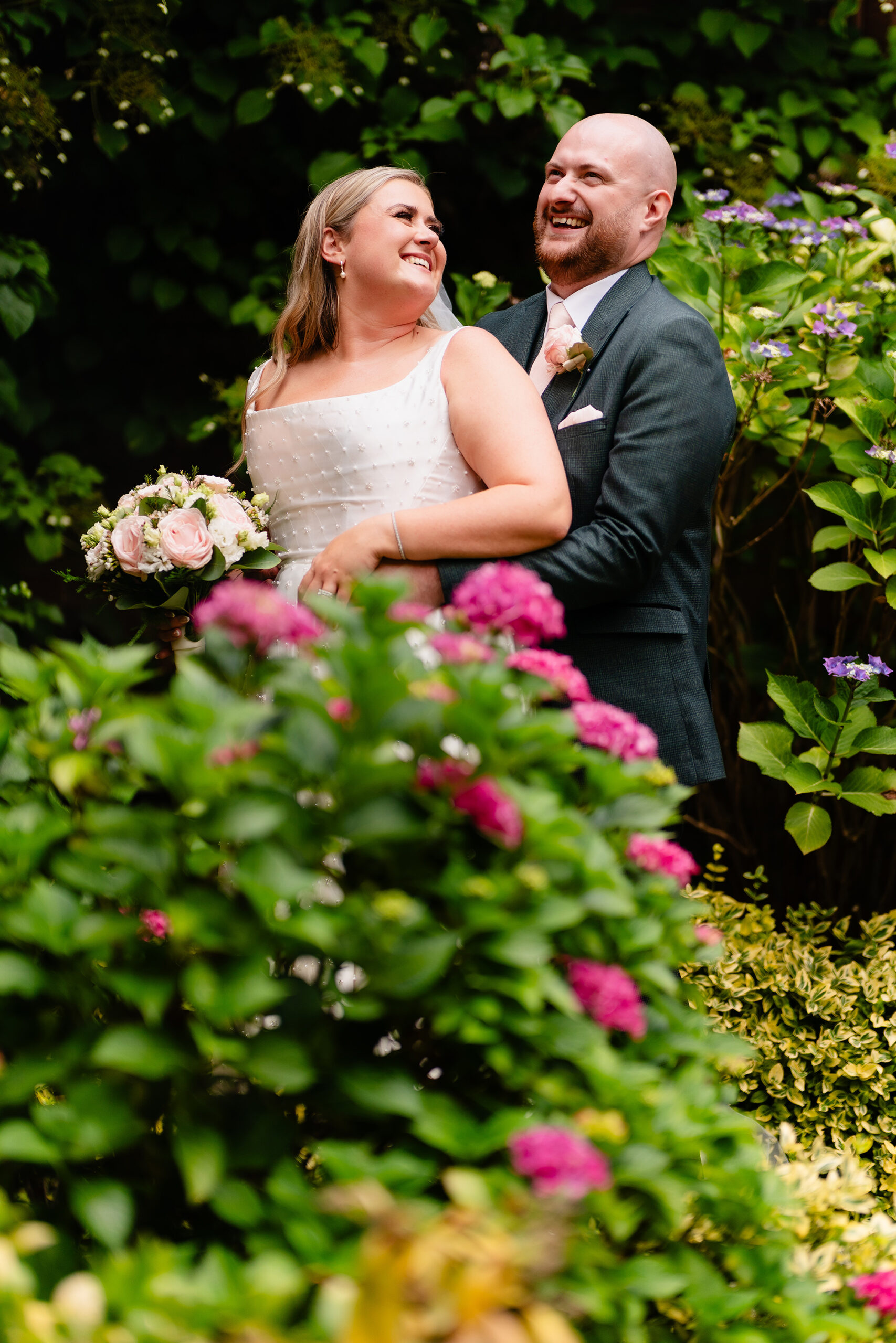 Pete and Chloe sharing a kiss in the hydrangea garden at Wrenbury Hall