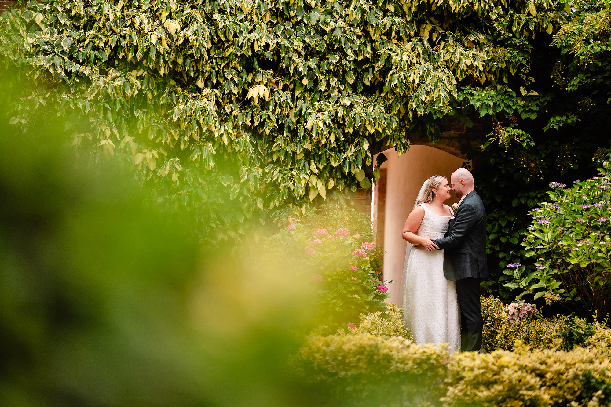 A creative through the leaves portrait of Chloe and Pete in the Wrenbury Hall gardens