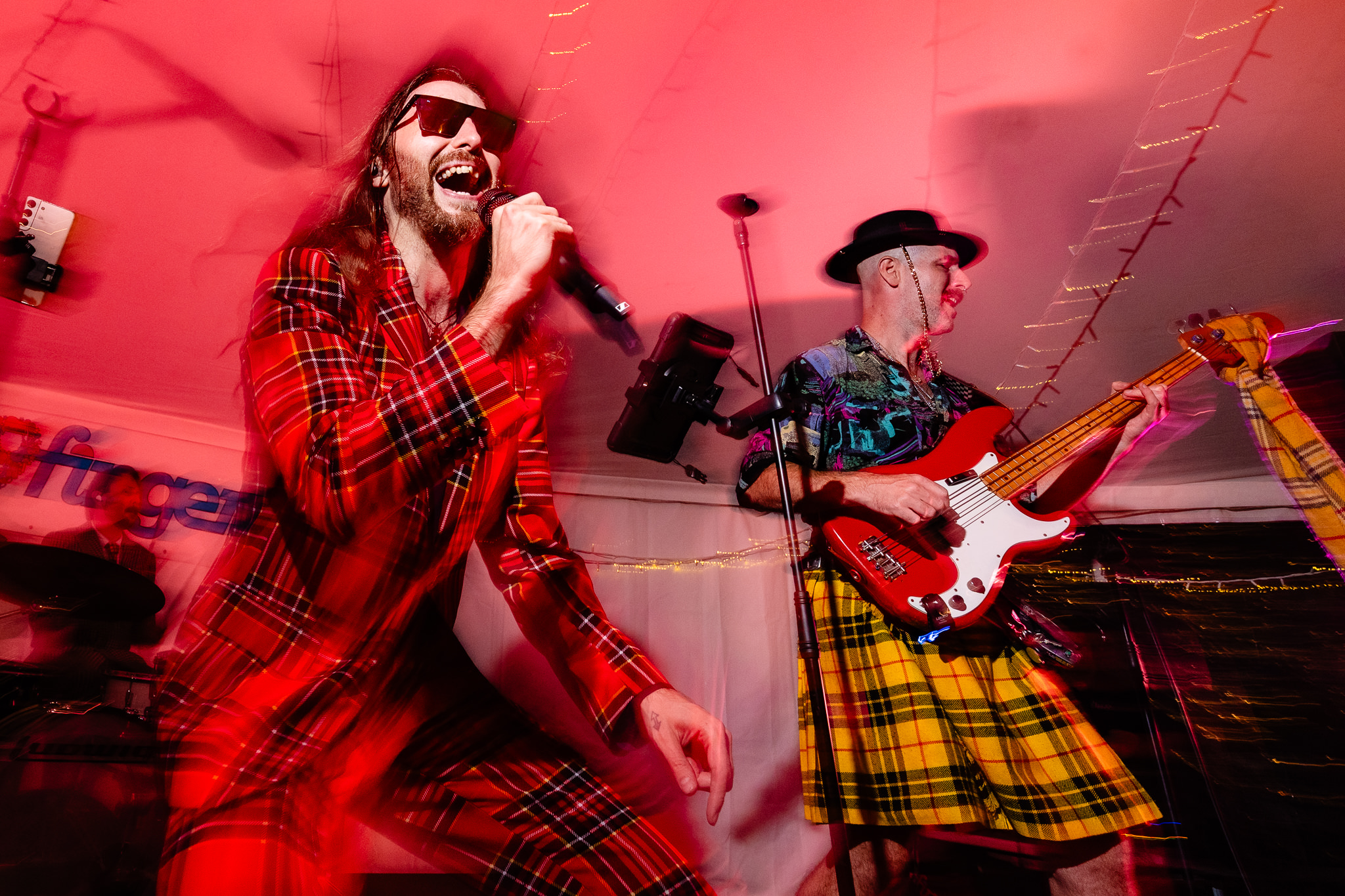 Wedding band singer in tartan performing under red stage lights