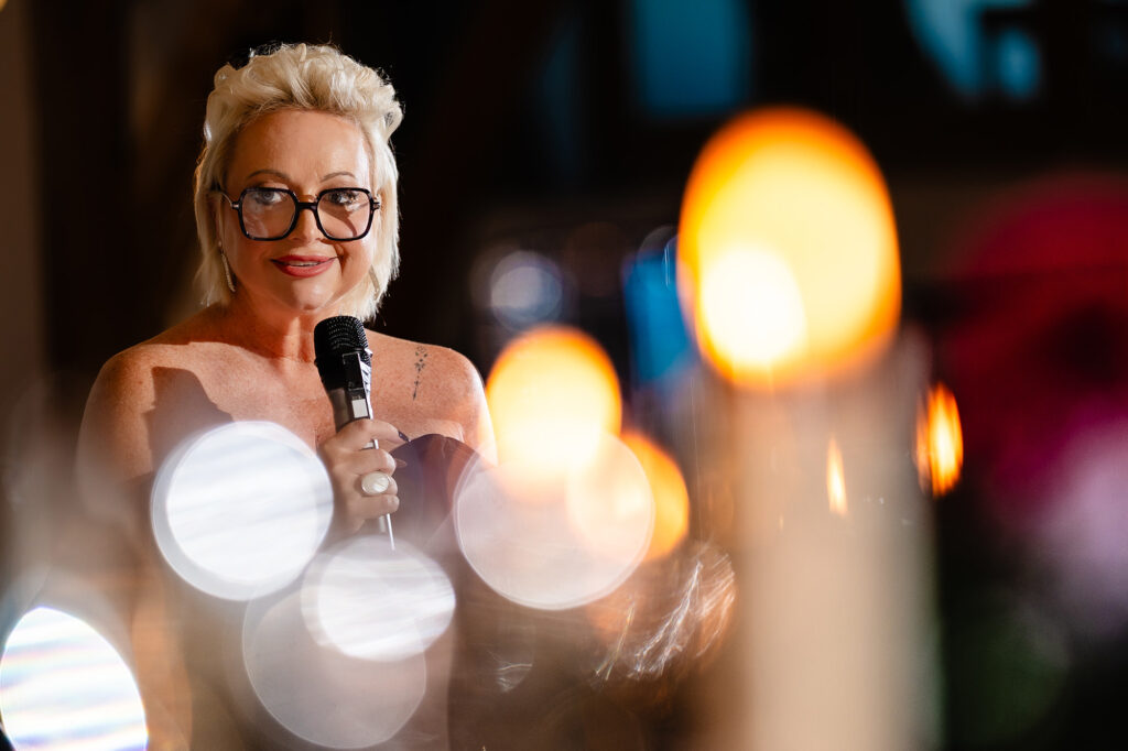 A guest in glasses giving a speech, candles glowing in the foreground, Nottingham wedding photographer