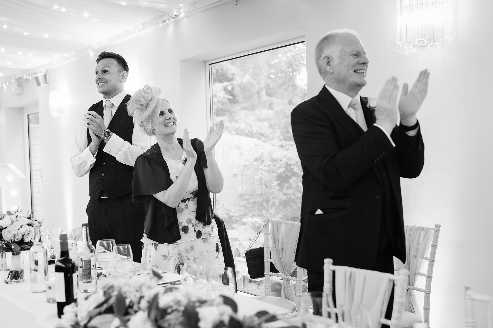 Guests laughing during the wedding speeches at Wrenbury Hall, black and white