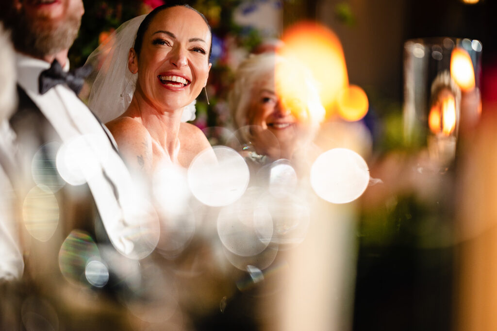 Kim laughing during the speeches through candle light, Nottingham wedding photographer