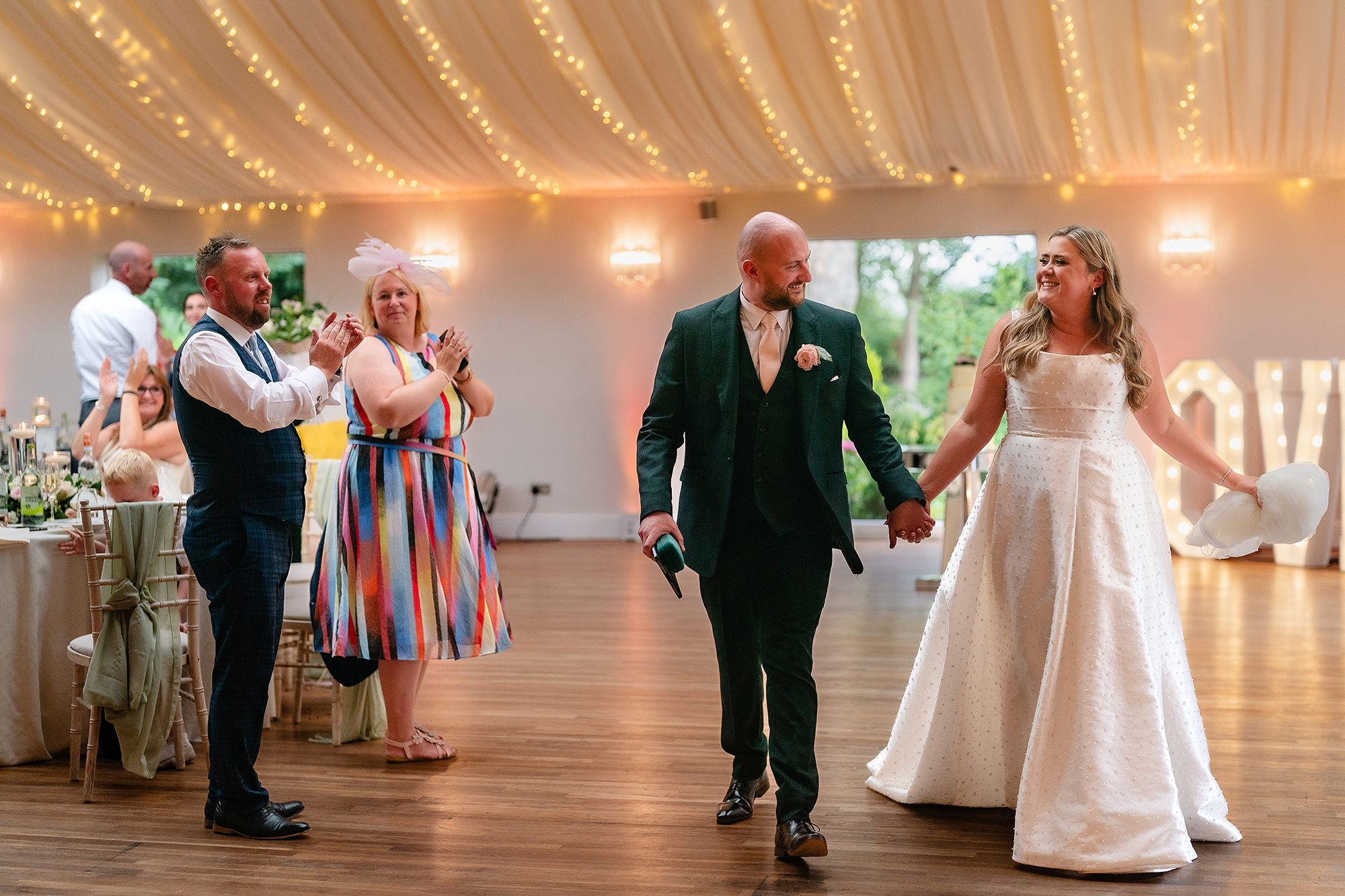 Chloe and Pete arriving into the marquee under the fairy lights to applause
