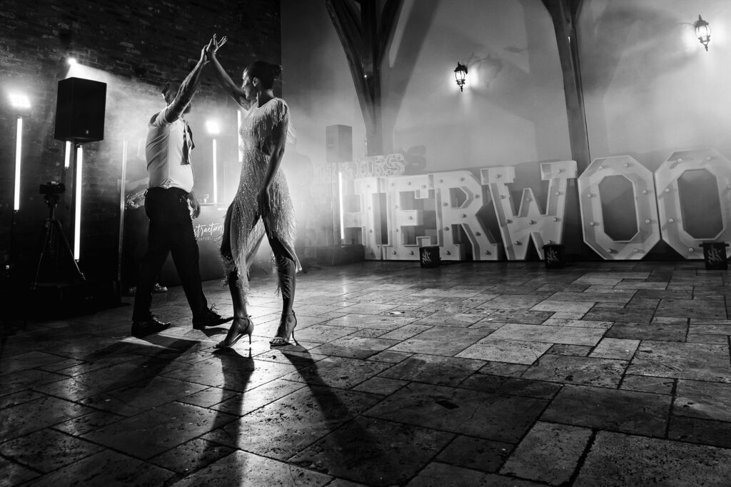 Black and white of the first dance in smoke in front of the SHERWOOD light up letters, Nottingham wedding photographer