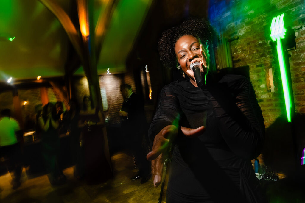 The band's singer performing under green light on the dance floor, Swancar Farm wedding photographer