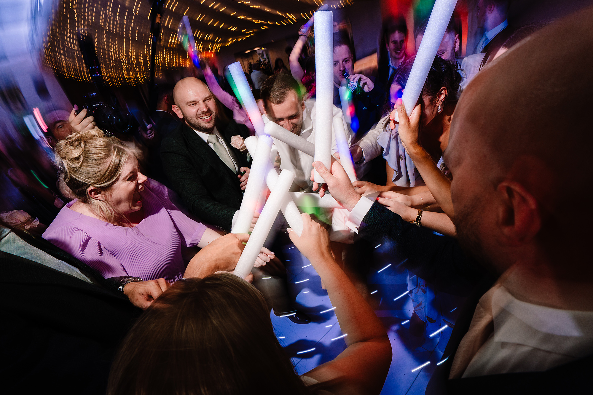 Guests cheering under colourful lighting on the Wrenbury Hall dancefloor