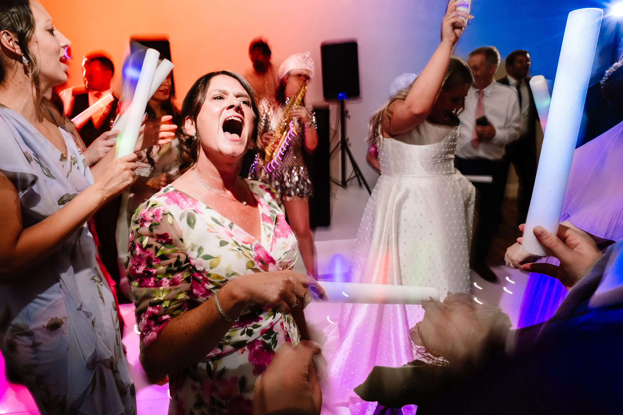 Guests cheering with glow sticks under colourful lighting as the saxophonist plays in the background at Wrenbury Hall
