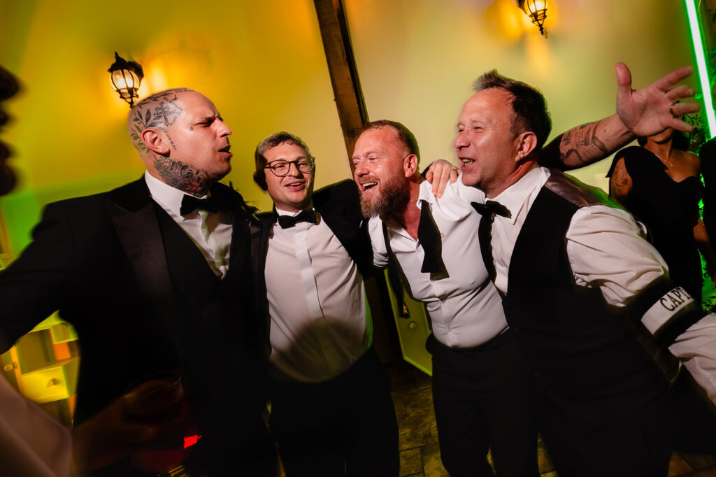 Groomsmen singing arm in arm on the dance floor, Swancar Farm wedding photographer