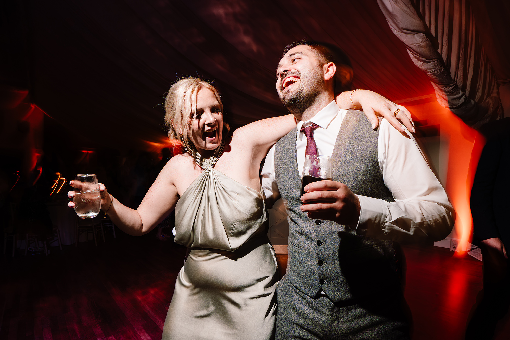 Two guests sharing a laugh together on the dancefloor during the evening party at Wrenbury Hall