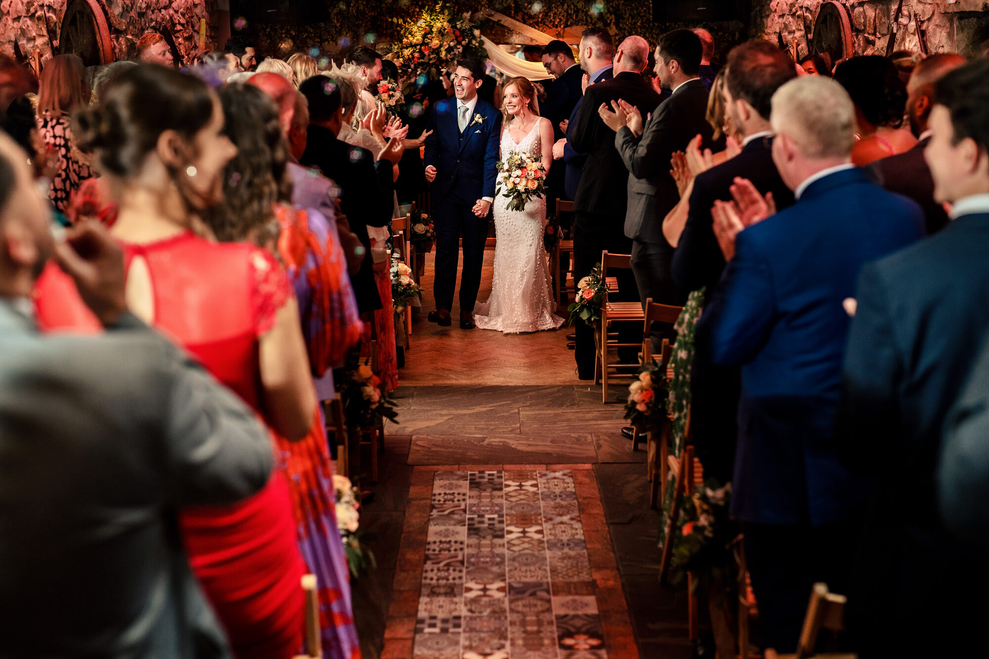 Bride walking down the aisle of a candlelit barn in autumn