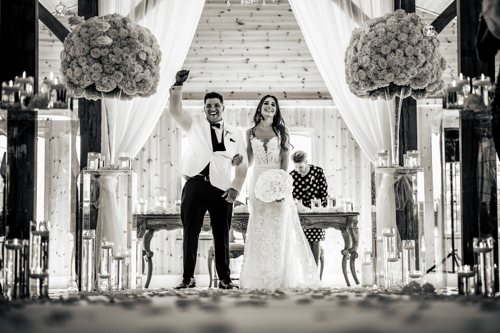 Black and white photograph of a groom punching the air at the altar