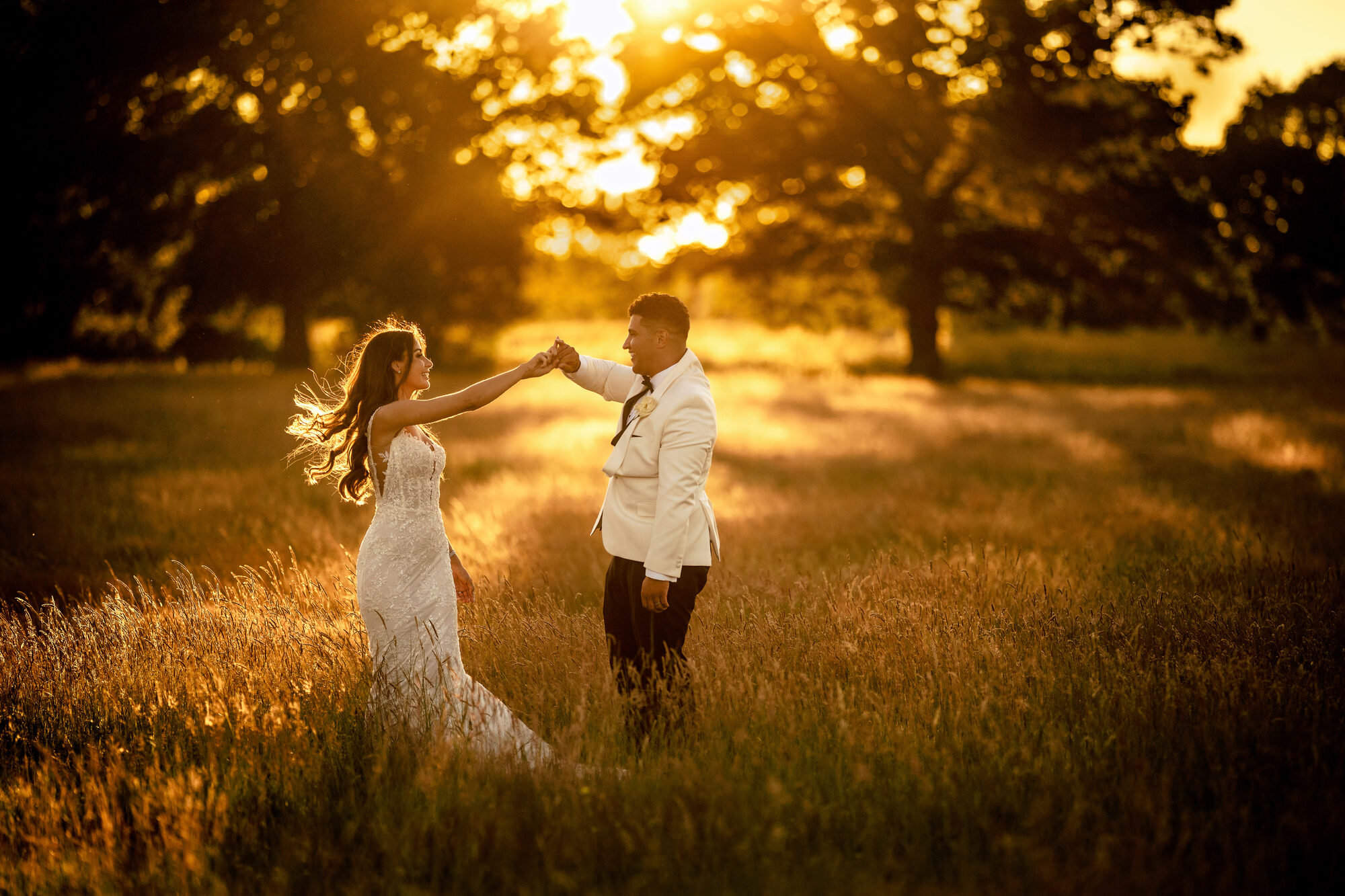 Bride and groom dancing together in a meadow of golden light