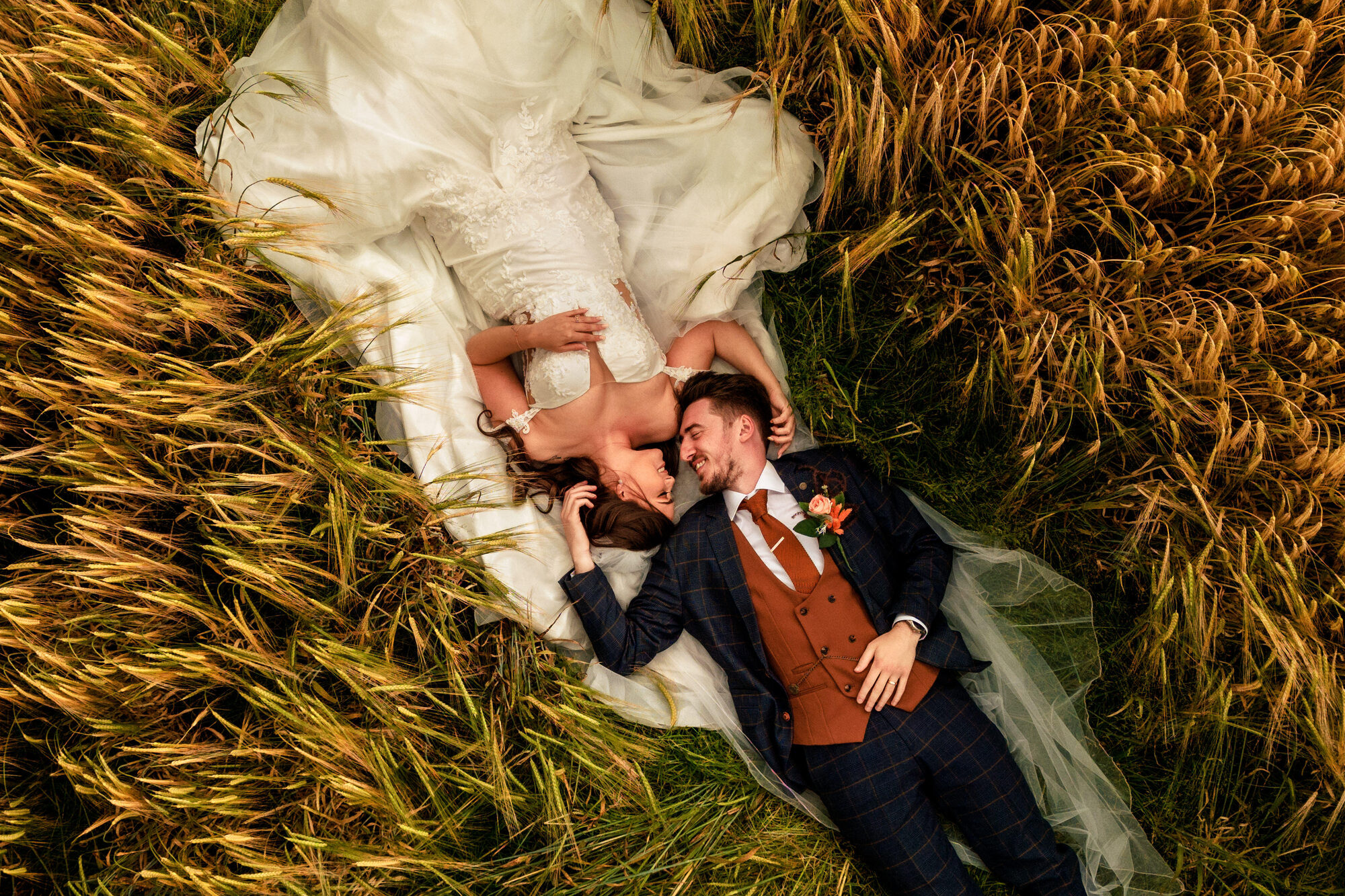 Bride and groom lying together in a cornfield, photographed from above