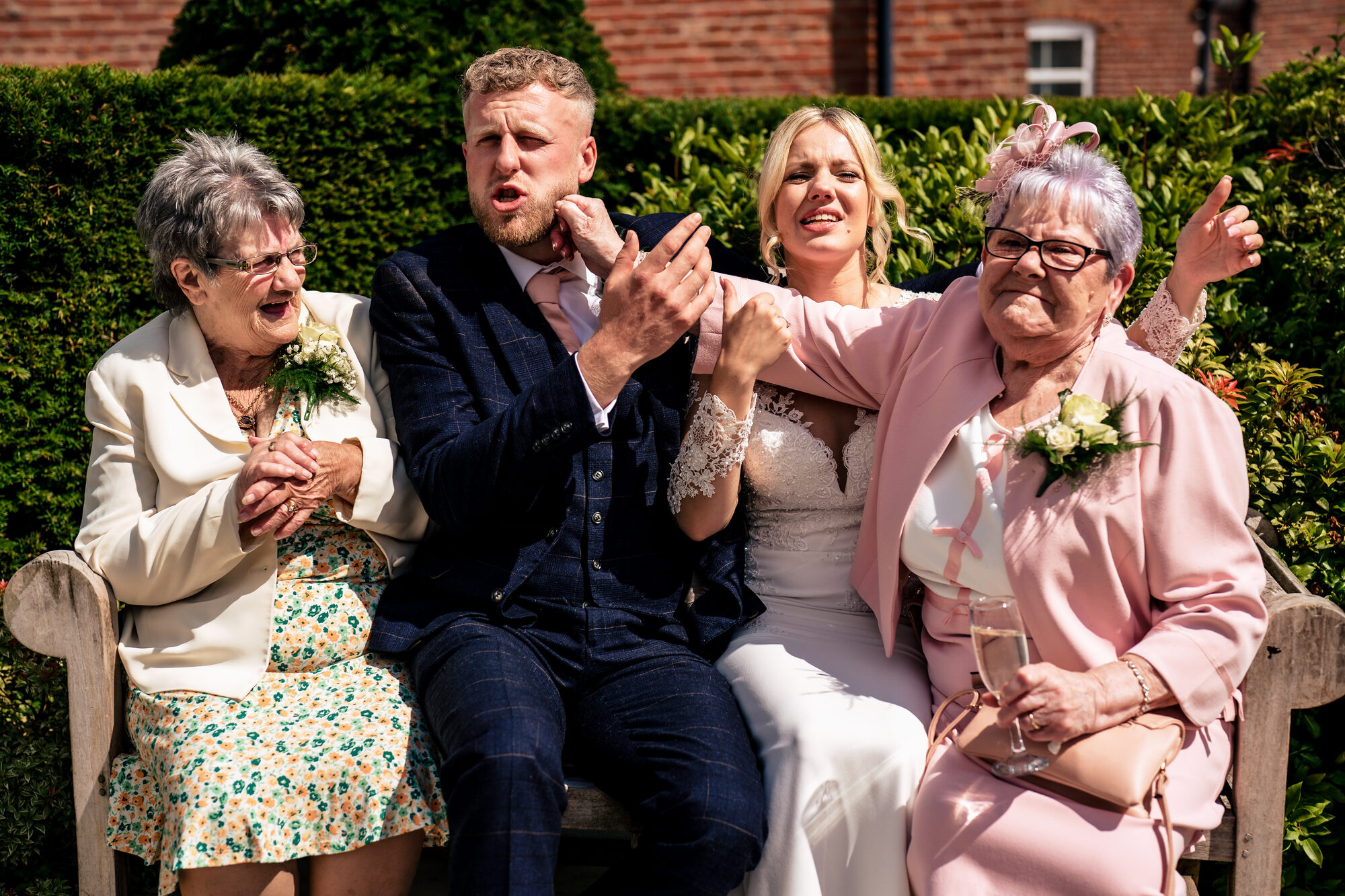 Bride and groom squeezed onto a bench between their grandmothers