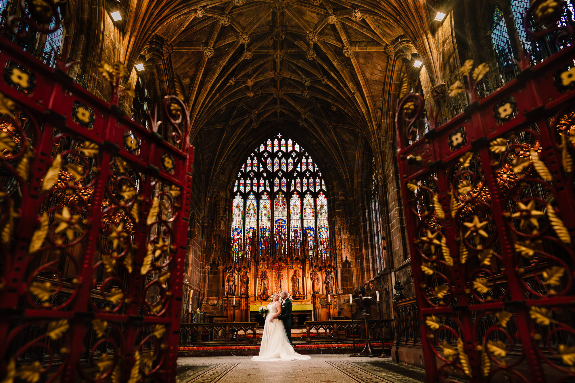 Bride and groom dwarfed by the vaulted ceiling of a cathedral