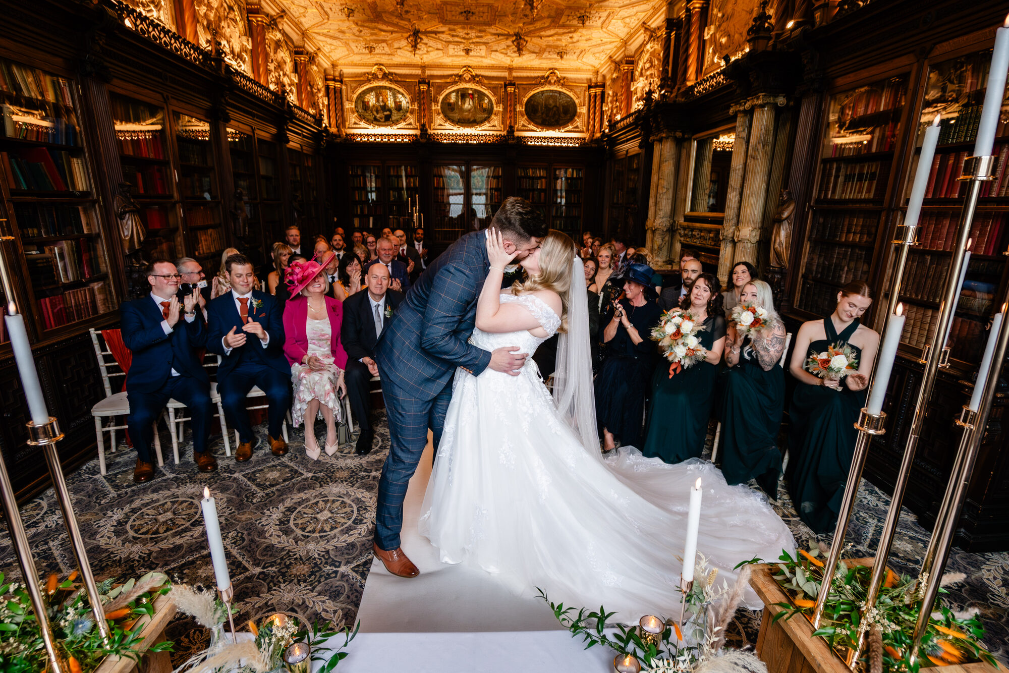 Bride and groom's first kiss in an ornate gilded library