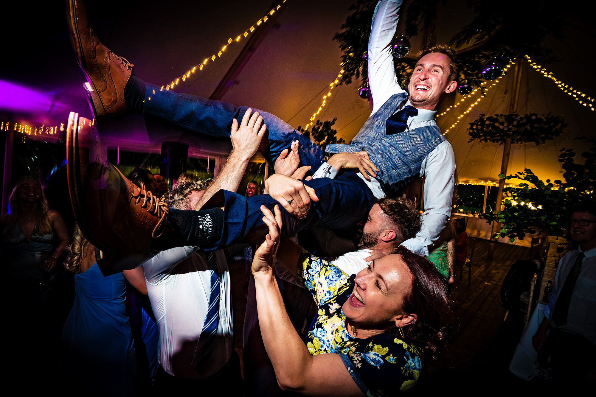 Groom being lifted into the air by his guests on the dance floor