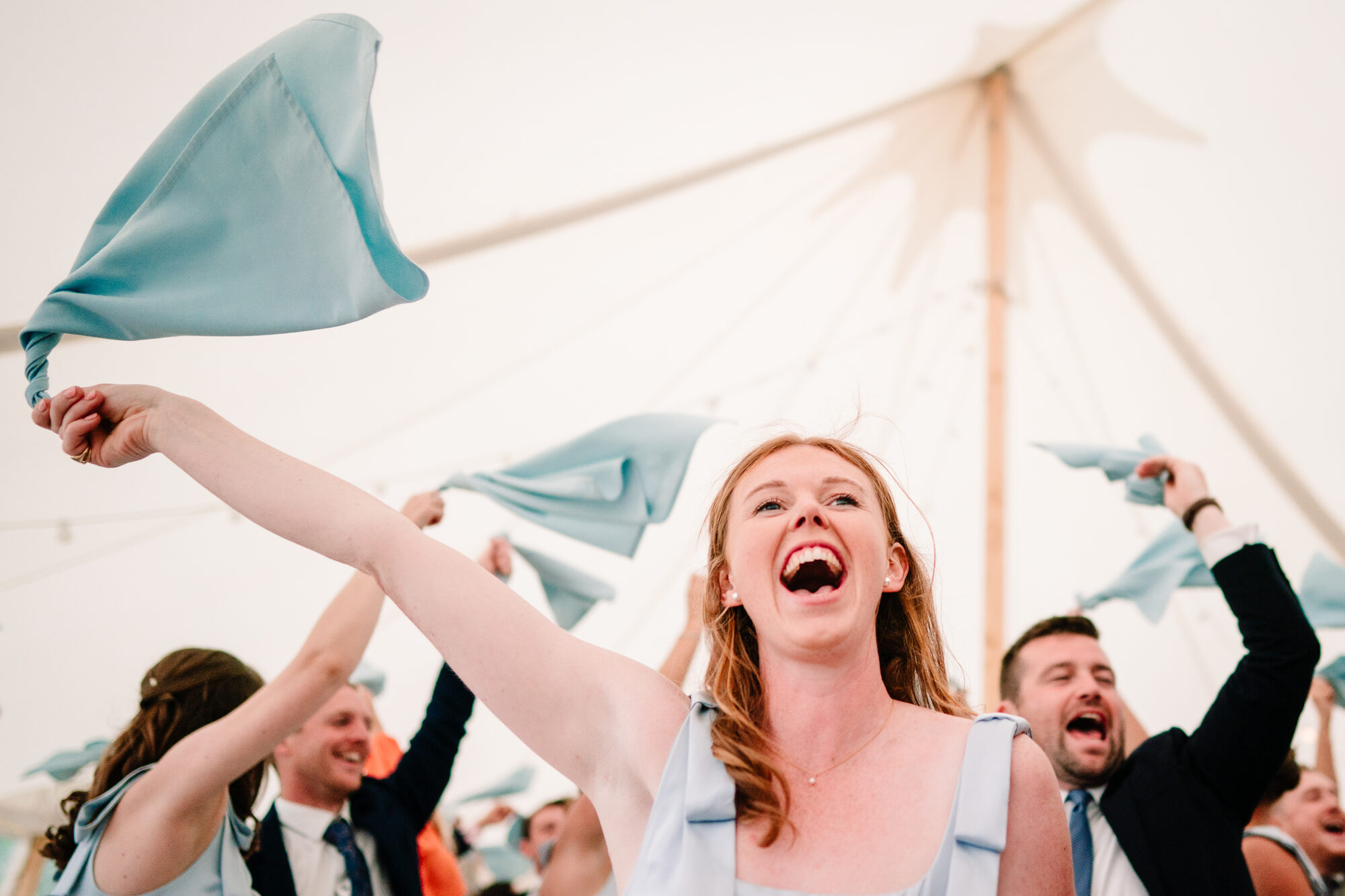 Wedding guest cheering and waving her napkin in a marquee