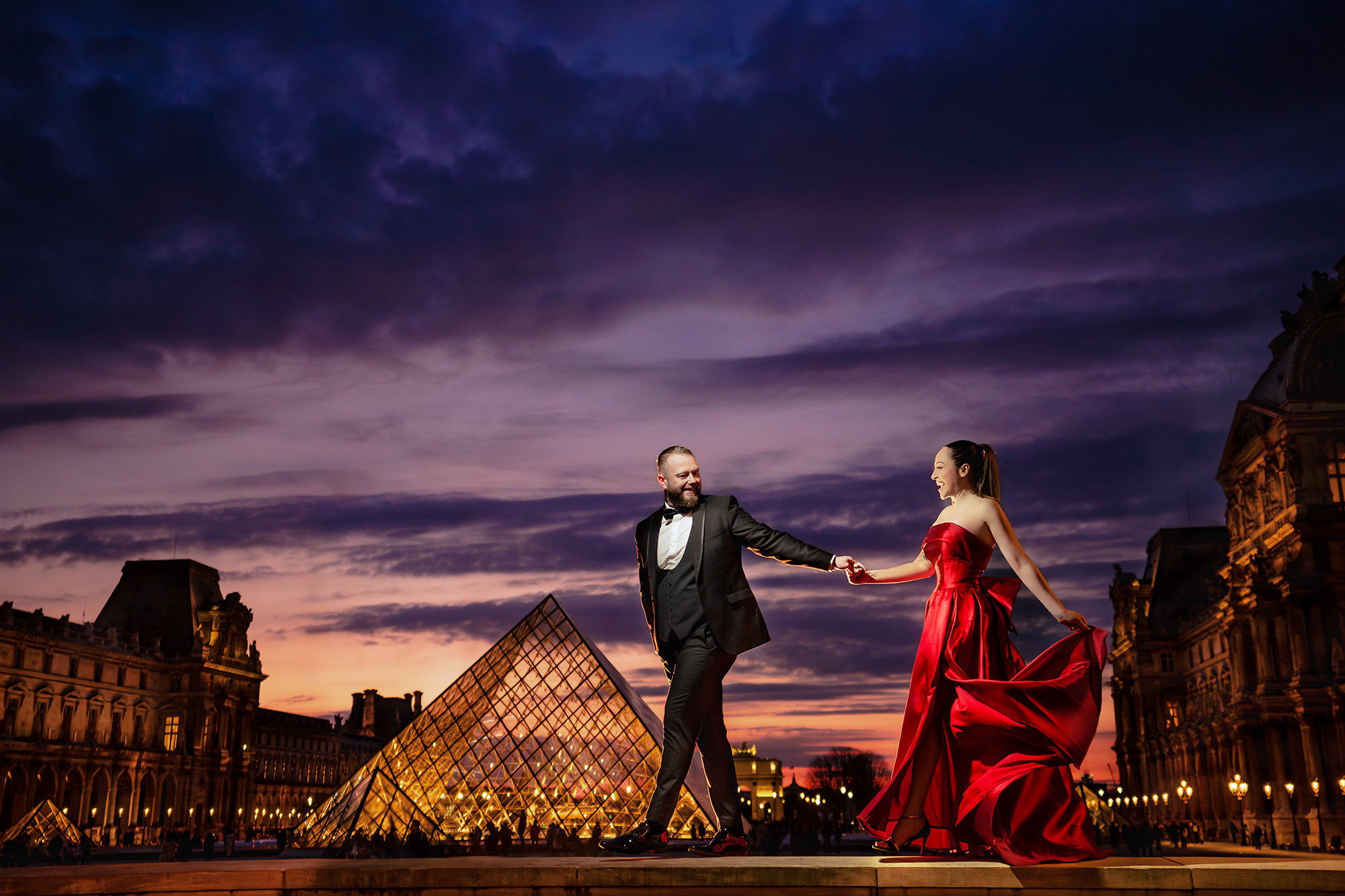 Bride in a red dress with her groom outside the Louvre at sunset