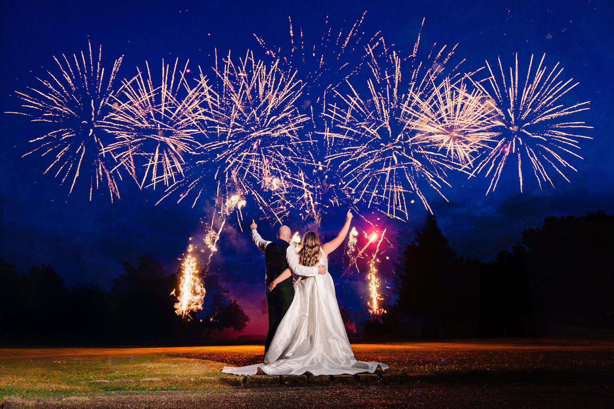 Bride and groom watching fireworks explode above them