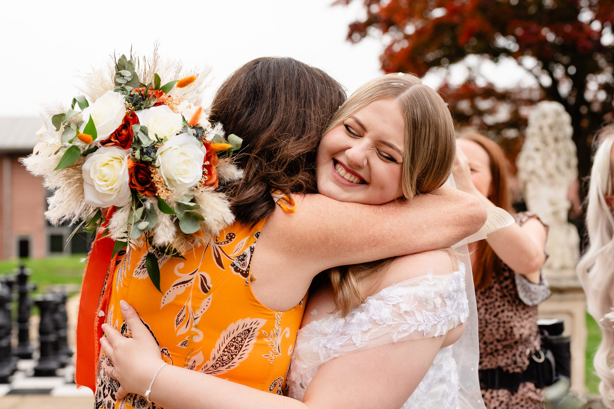 Wedding guest throwing her arms around the bride outside