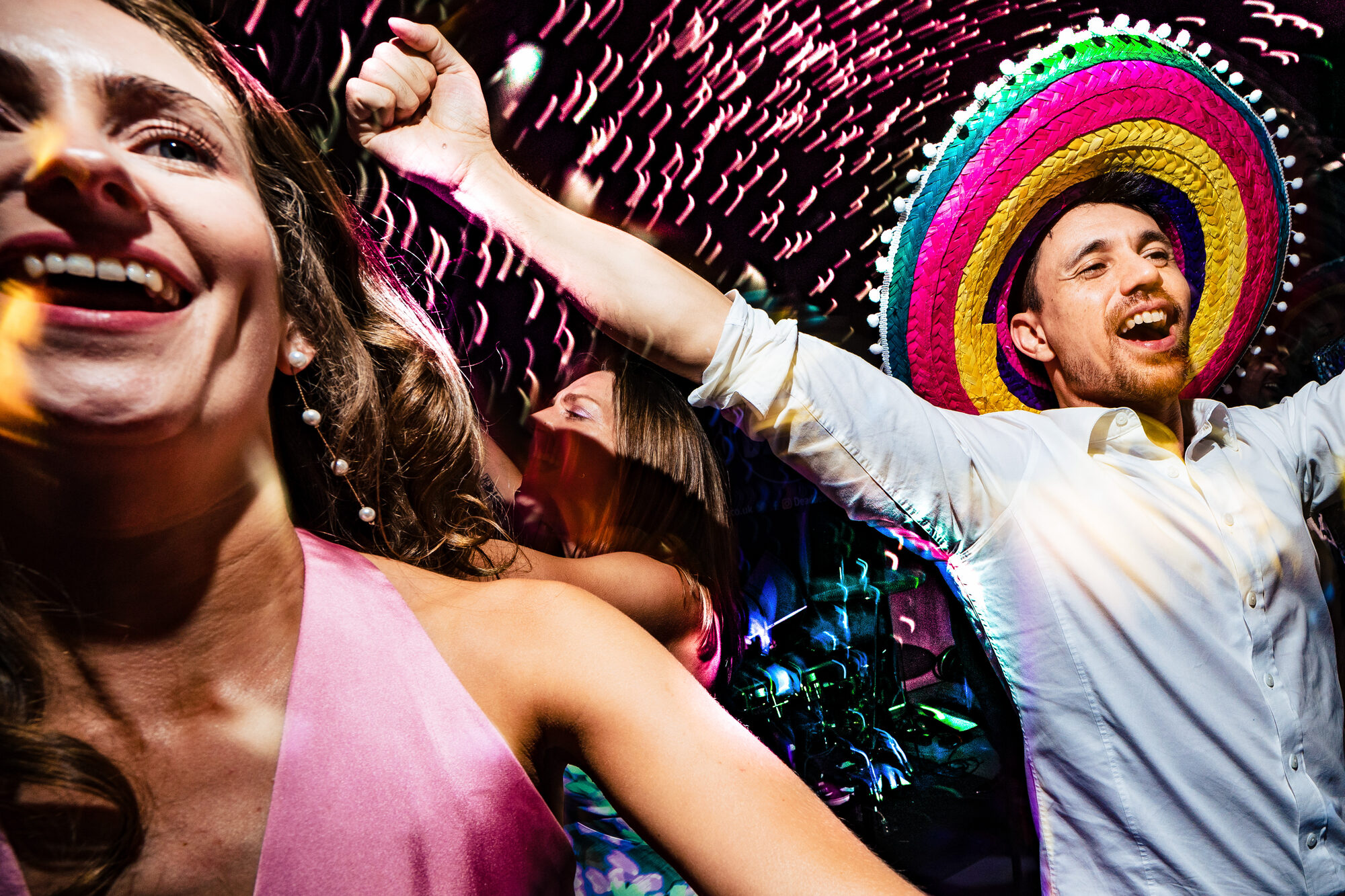 Wedding guests in sombreros laughing on the dance floor