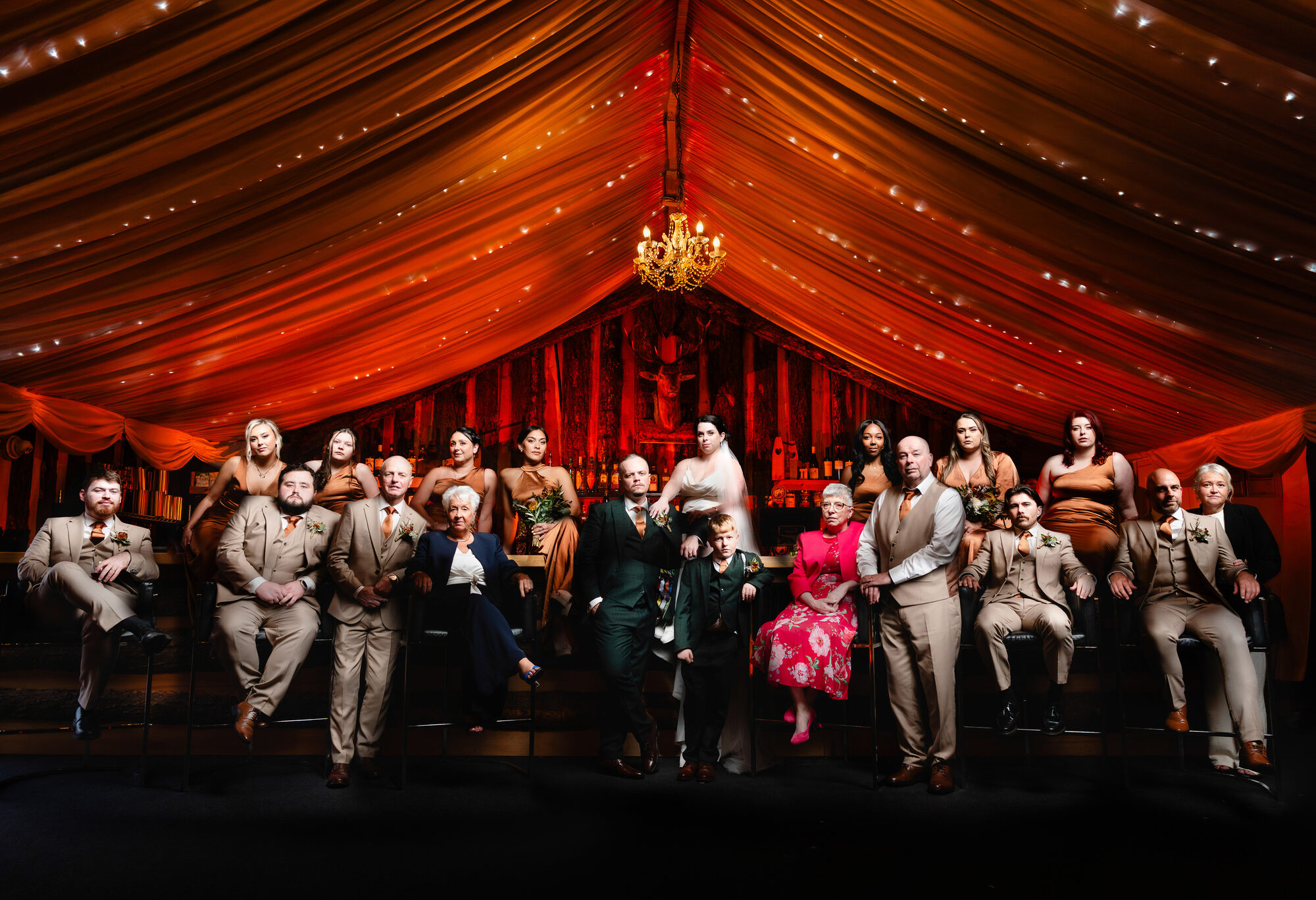 The whole wedding party photographed together in a marquee