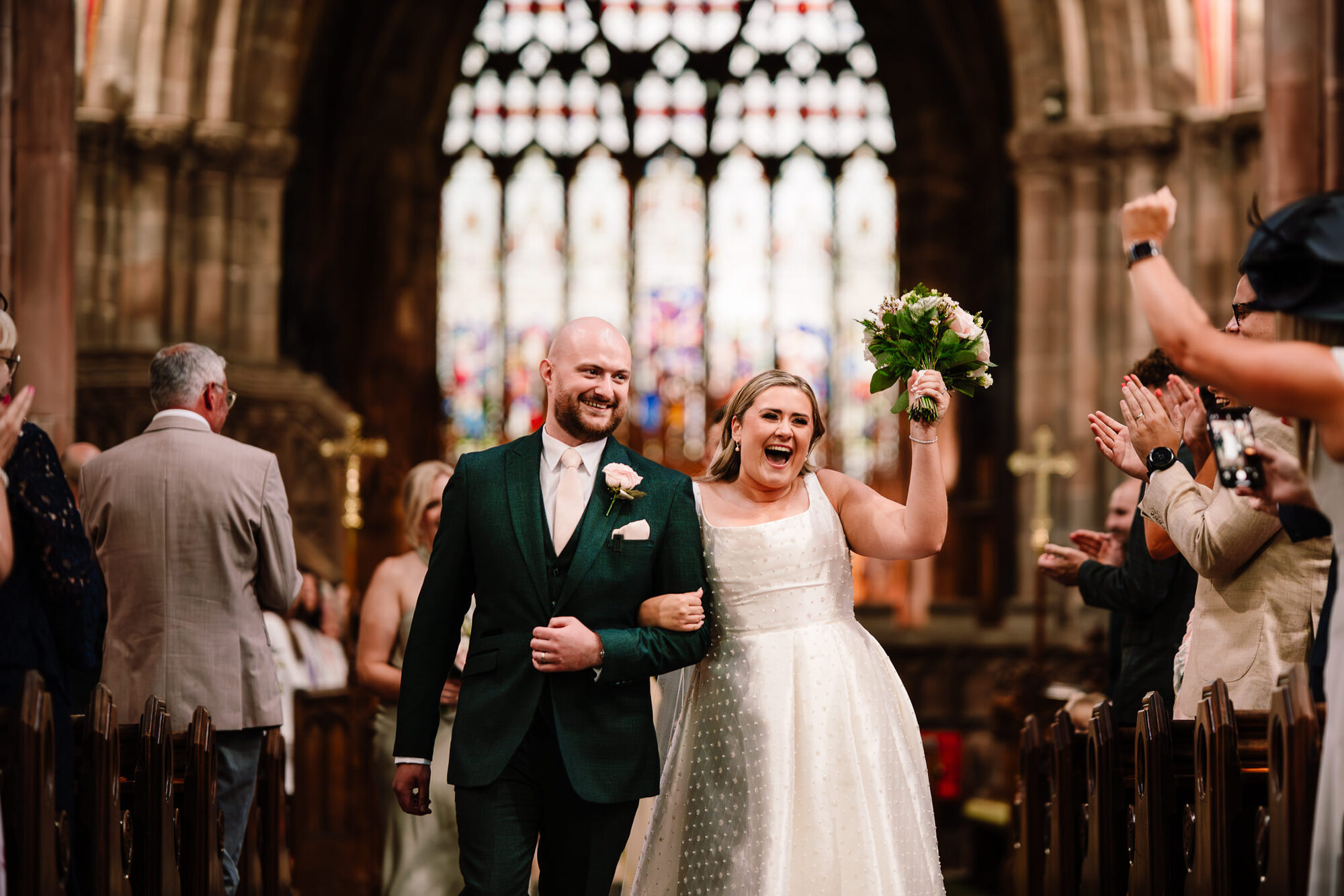 Bride cheering as she walks back down the aisle with her husband
